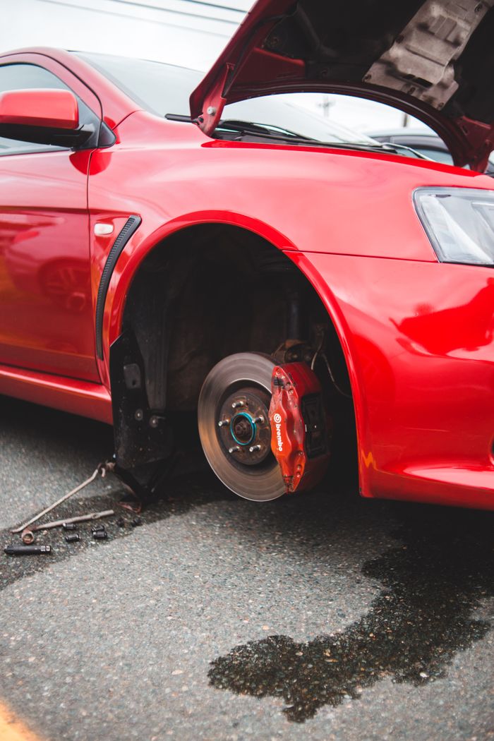 Services Close-up of a red car with the wheel removed, exposing the brake disc during repair.