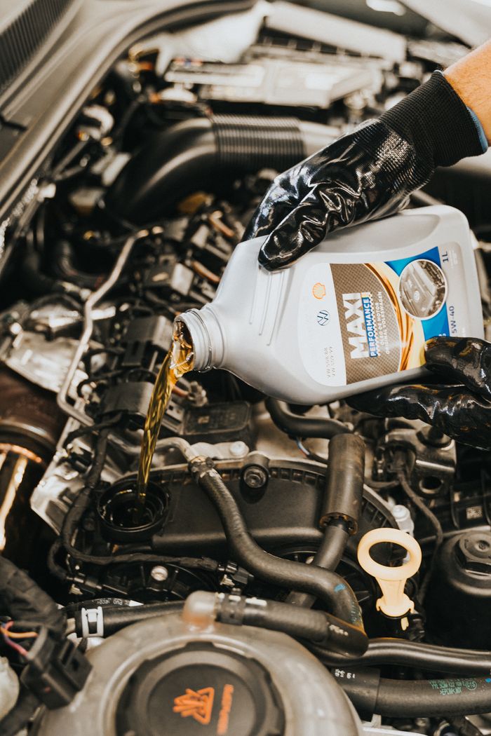 Mastering the First Impression: Your intriguing post title goes here Close-up of mechanic pouring engine oil into car engine with gloved hands, showcasing automotive maintenance.