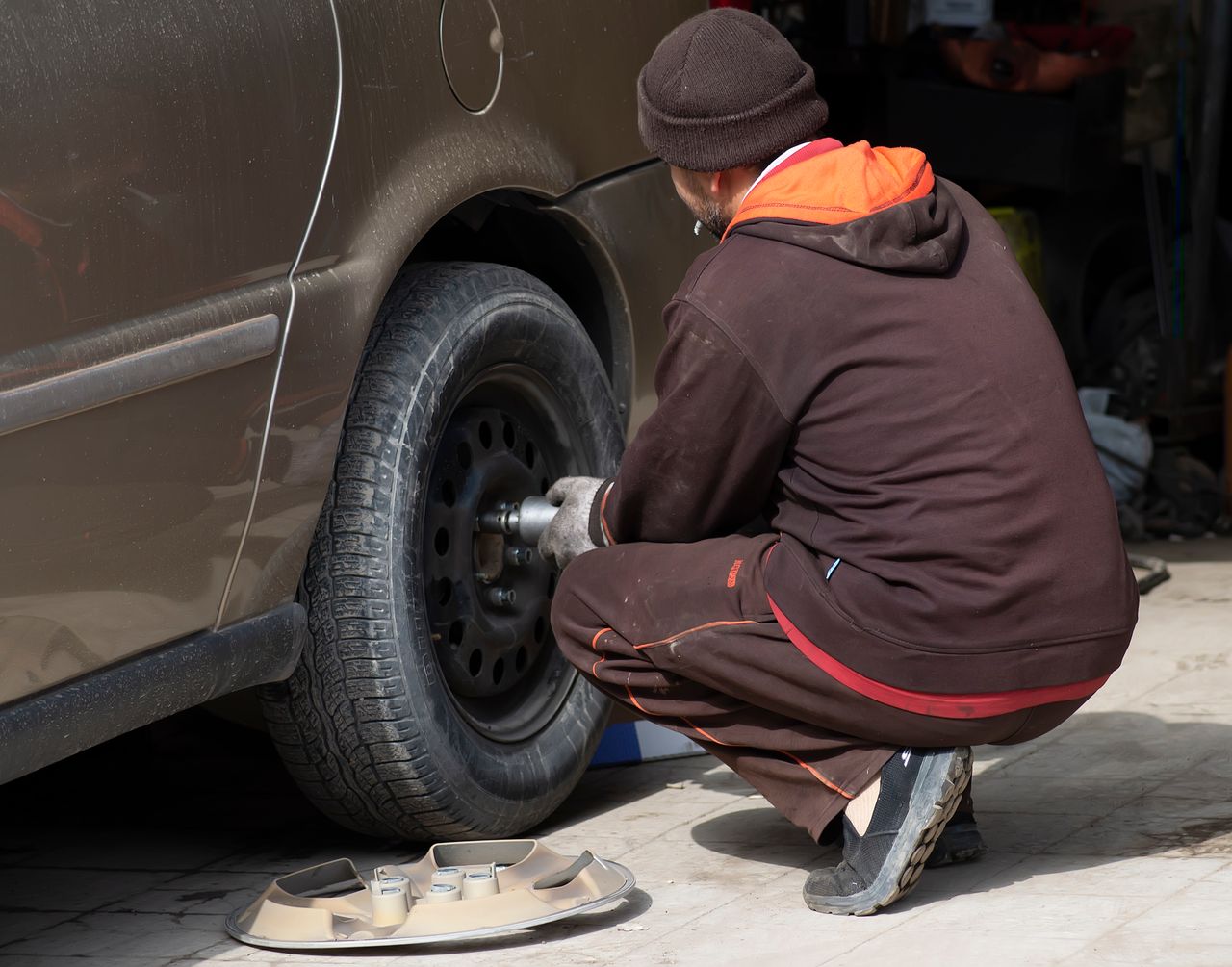 Services A mechanic working on a car tire, changing it in an auto repair shop.