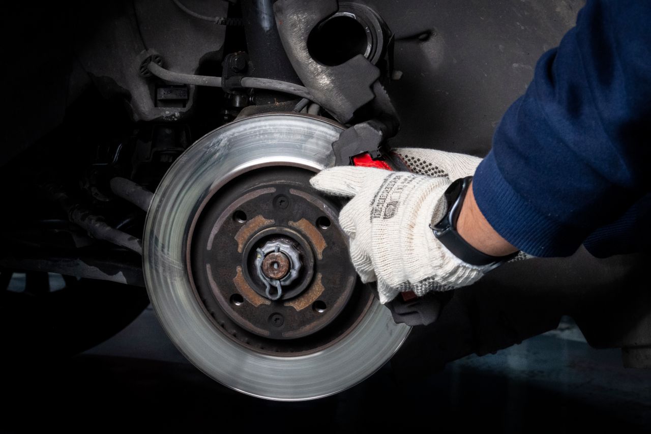 Services Mechanic working on car brake system in a workshop setting.