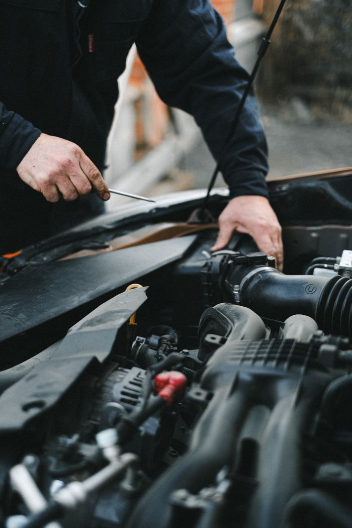 About A mechanic working on a car engine with tools, focused on repairs.