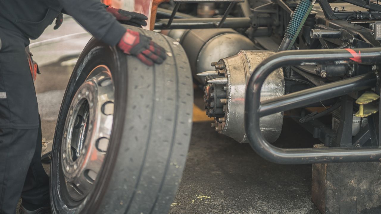 Services Mechanic working on replacing a tire in a professional automotive garage setting.